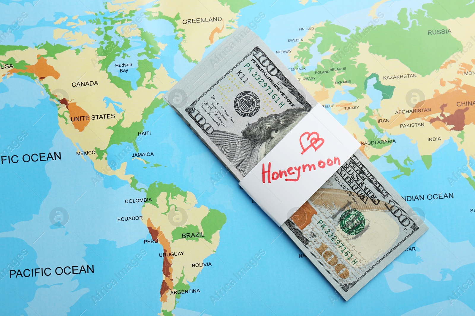 Photo of Stack of money with word Honeymoon on world map, top view