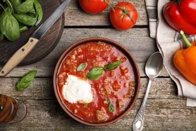 Bowl of delicious stuffed pepper soup on wooden table, flat lay