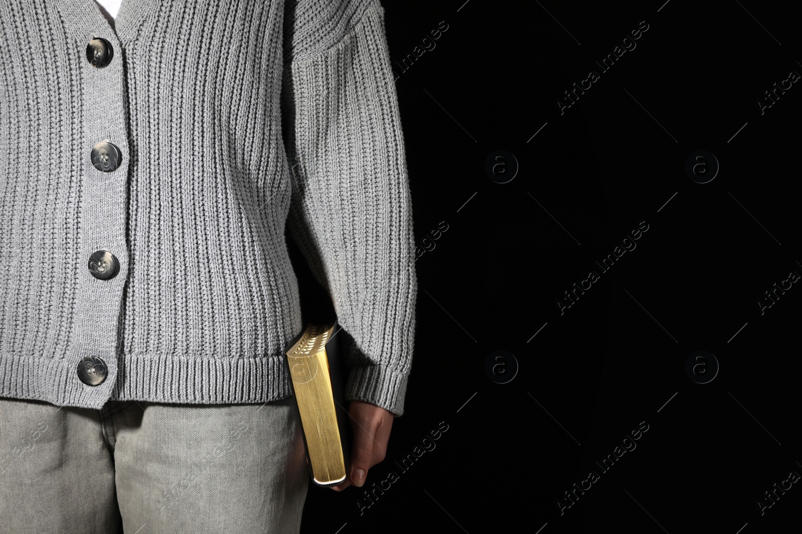 Photo of Woman holding Bible against black background, closeup. Space for text