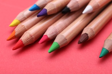 Photo of Many colorful pastel pencils on red background, closeup. Drawing supplies