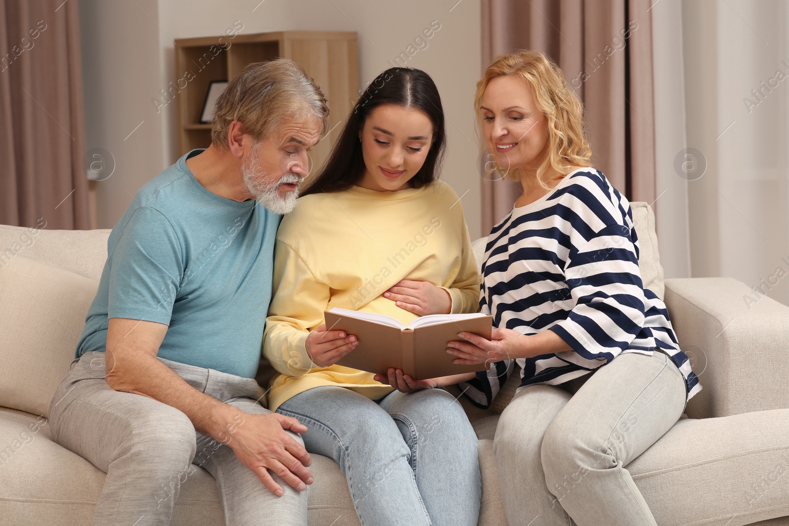 Photo of Happy pregnant woman spending time with her parents at home. Grandparents' reaction to future grandson