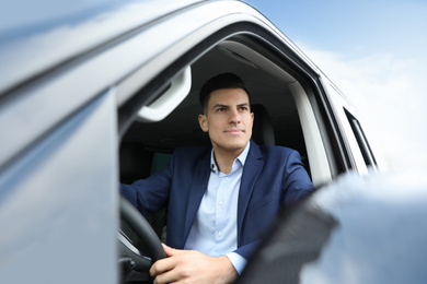 Photo of Handsome man driving his modern car, view from outside