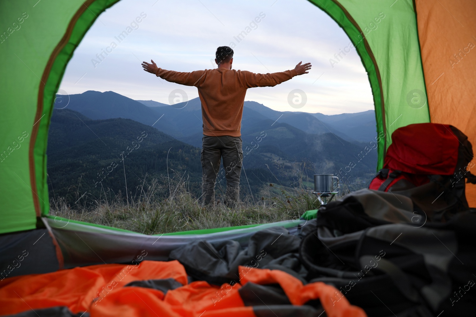 Photo of Man enjoying mountain landscape, view from camping tent