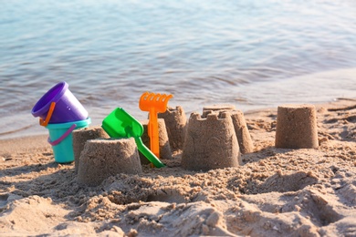 Photo of Little sand figures and plastic toys on beach near sea