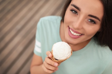 Photo of Happy young woman with delicious ice cream in waffle cone outdoors