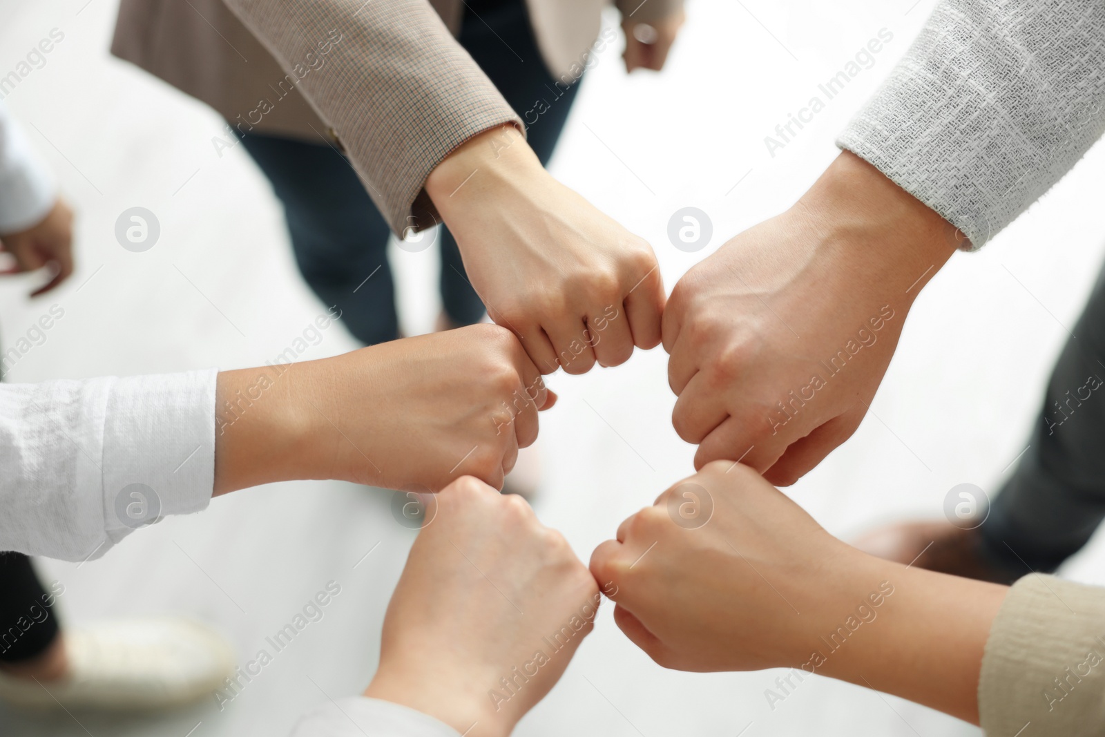 Photo of Group of people holding fists together indoors, above view. Unity concept