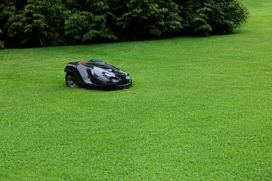 Photo of Modern lawn mower on green grass outdoors. Space for text