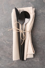 Set of stylish cutlery and napkin on grey textured table, top view