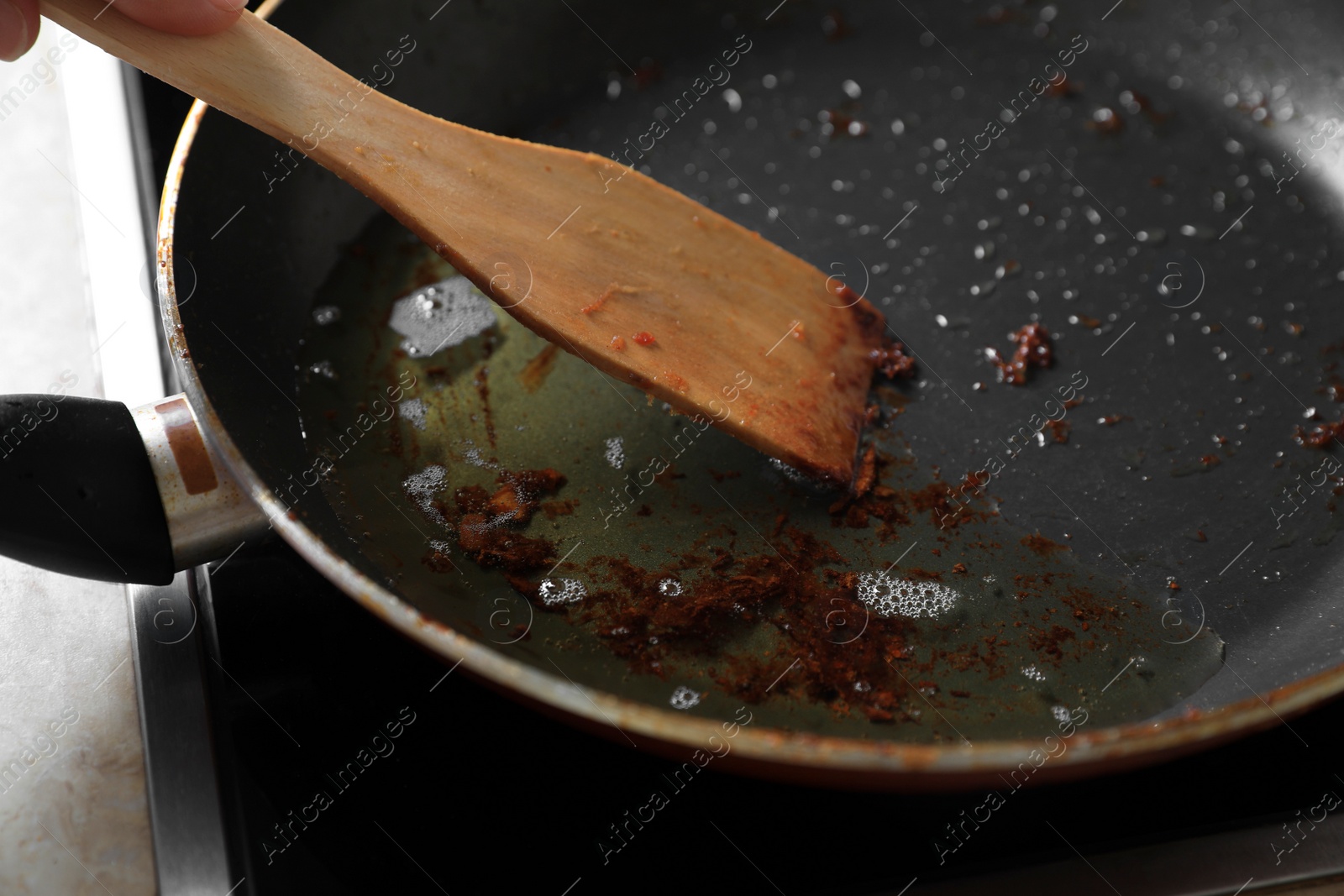 Photo of Frying pan with spatula and used cooking oil on stove, closeup