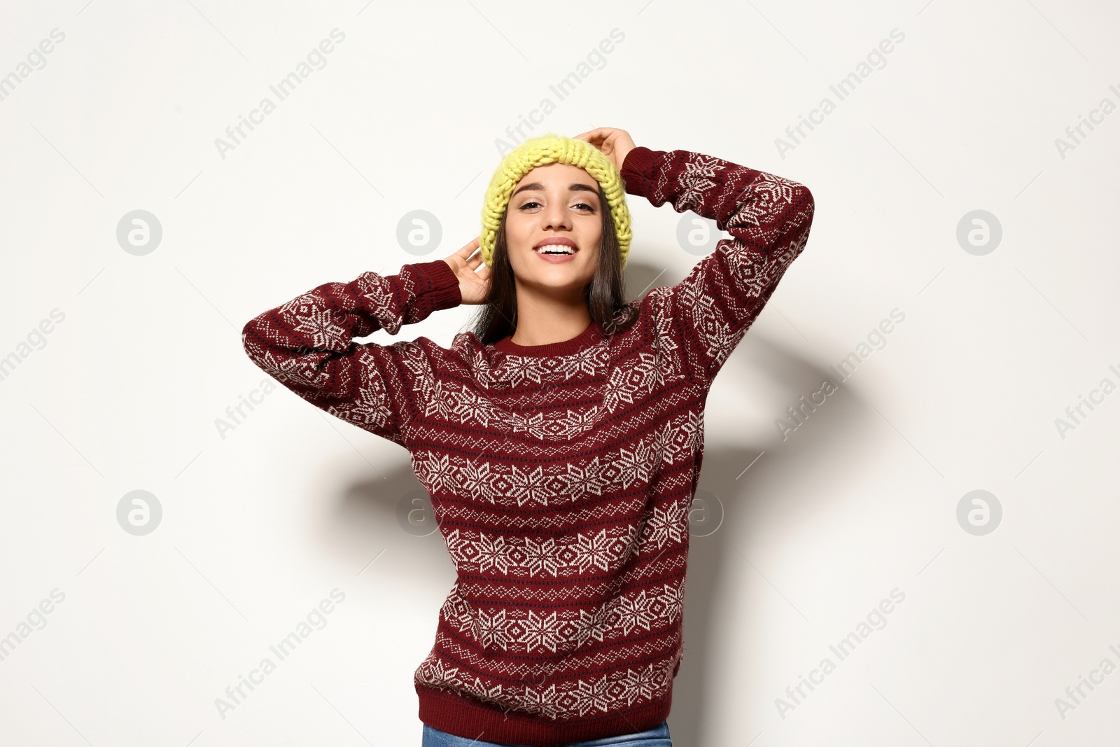 Photo of Young woman in warm sweater and knitted hat on white background. Celebrating Christmas