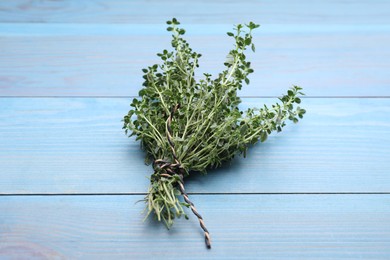 Photo of Bunch of aromatic thyme on light blue wooden table. Fresh herb