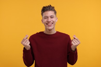 Photo of Happy man showing money gesture on yellow background