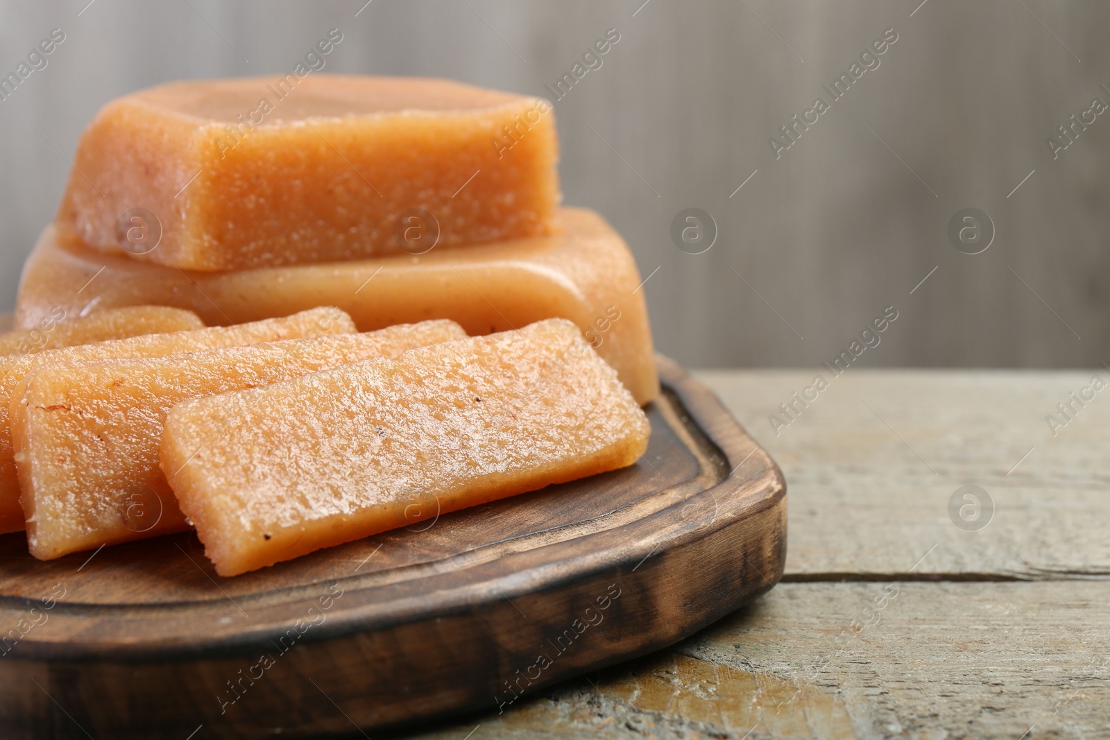 Photo of Tasty sweet quince paste on wooden table, closeup. Space for text