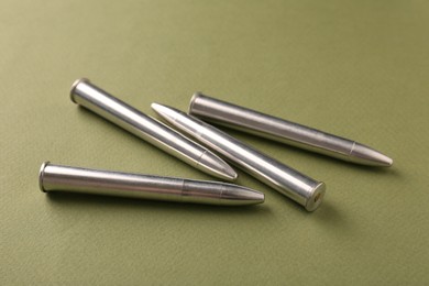 Photo of Many metal bullets on green background, closeup