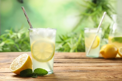 Photo of Natural lemonade with mint and fresh fruit on wooden table, space for text. Summer refreshing drink