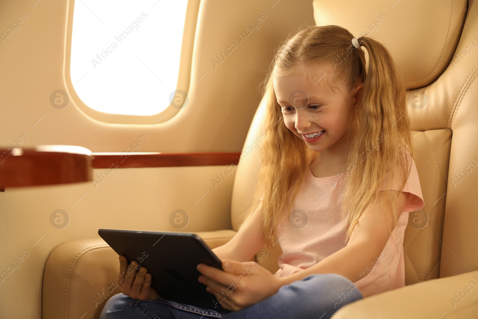 Photo of Cute little girl using tablet in airplane during flight