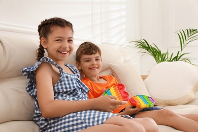Children playing with pop it fidget toys on sofa at home