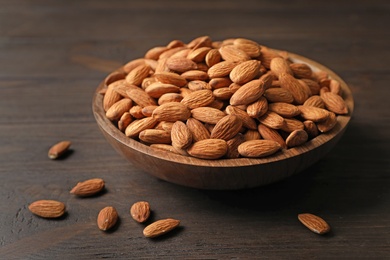 Photo of Tasty organic almond nuts in bowl on table