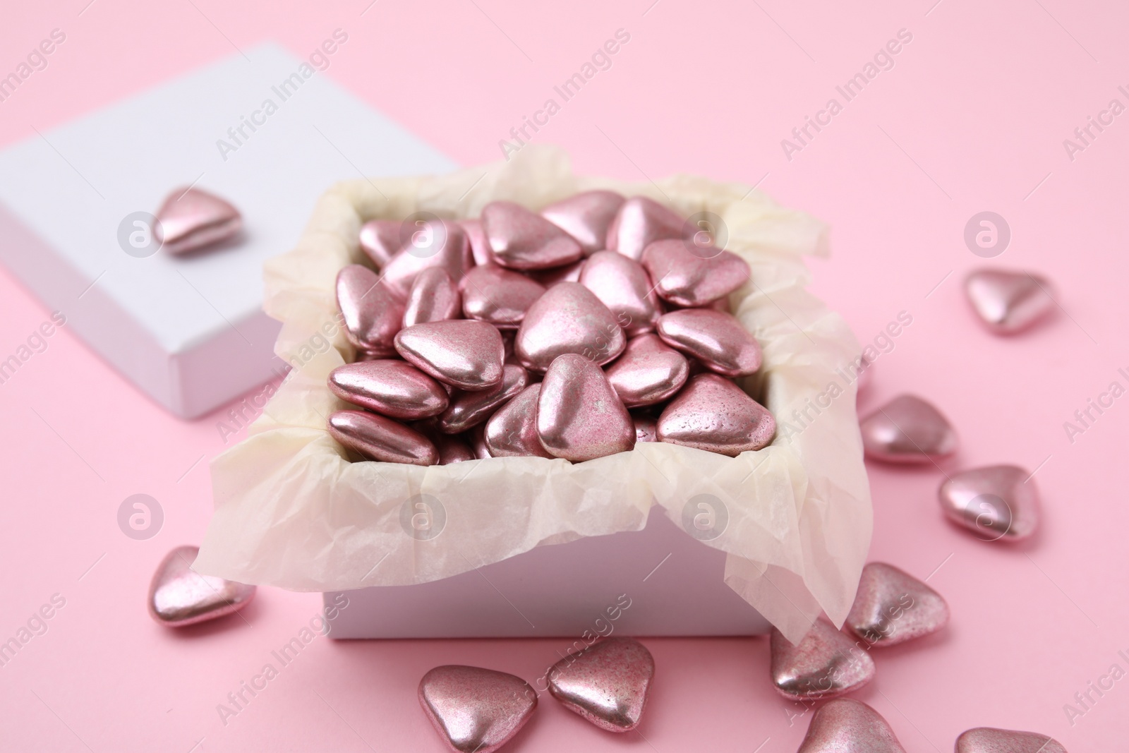 Photo of Box and delicious heart shaped candies on pink background