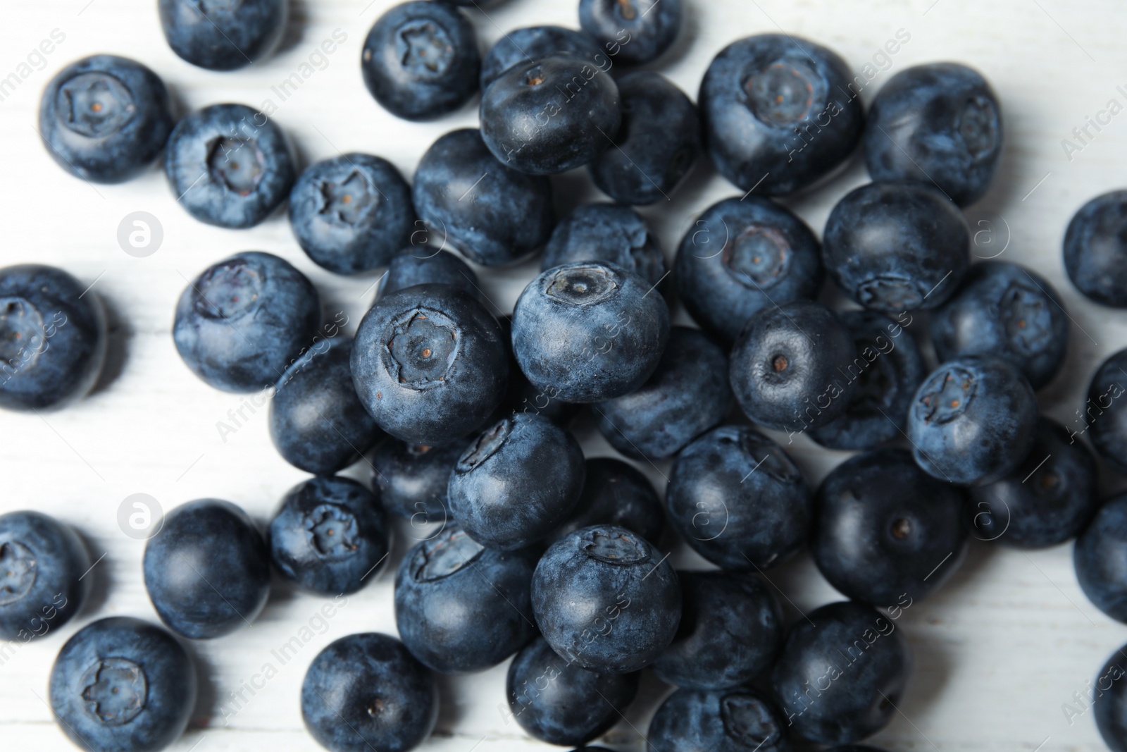 Photo of Pile of tasty fresh blueberries on white wooden table, top view