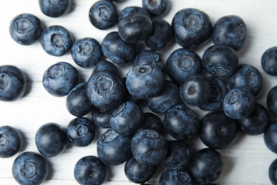 Pile of tasty fresh blueberries on white wooden table, top view