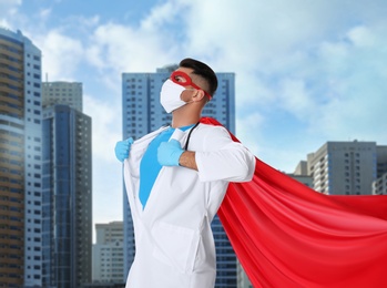Image of Doctor dressed as superhero on city background. Medical workers fighting with dangerous diseases