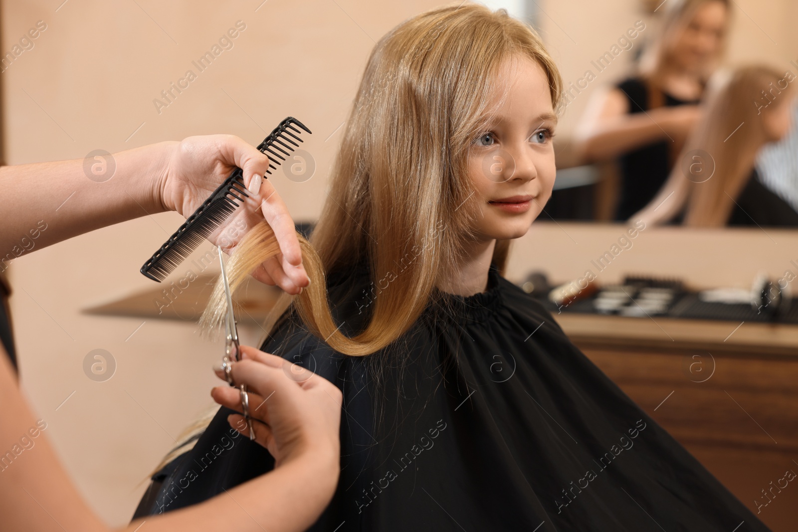 Photo of Professional hairdresser cutting girl's hair in beauty salon