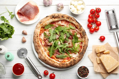 Tasty pizza with meat and arugula on white wooden table, flat lay