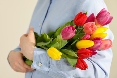 Woman holding beautiful colorful tulip flowers on white background, closeup