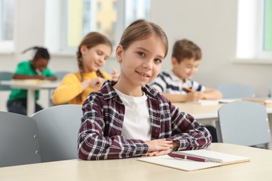 Photo of Smiling little girl studying in classroom at school