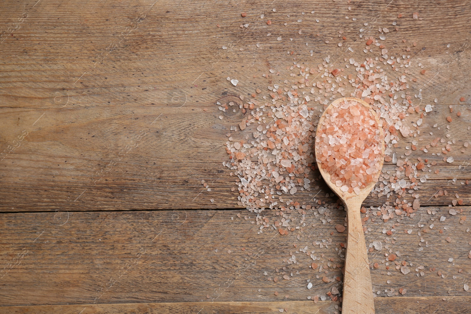 Photo of Pink himalayan salt on wooden table, flat lay. Space for text