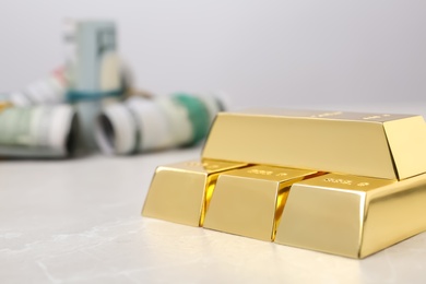 Photo of Shiny gold bars and dollar rolls on table, closeup. Space for text