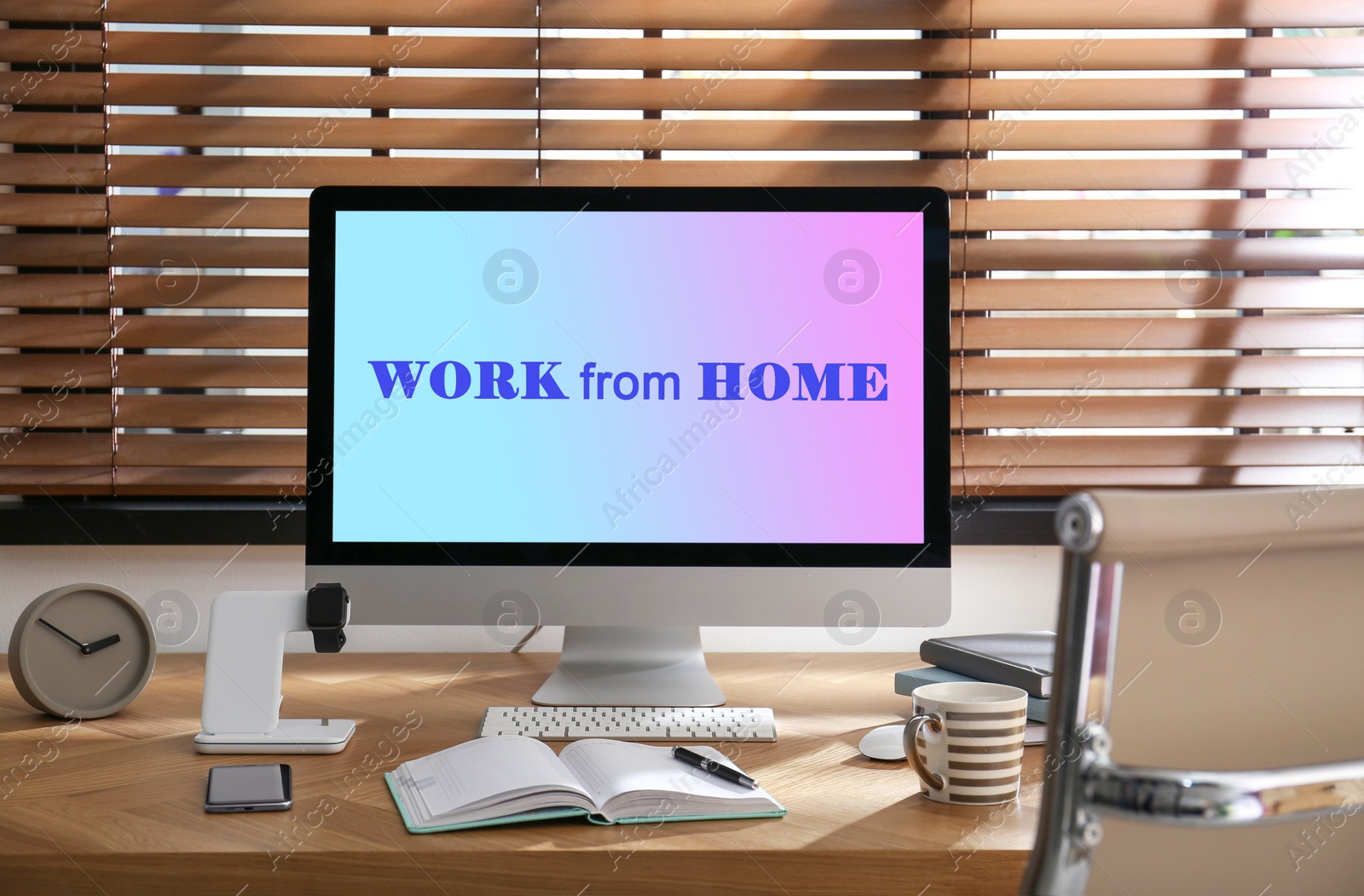 Image of Modern computer with text WORK FROM HOME on table in office 