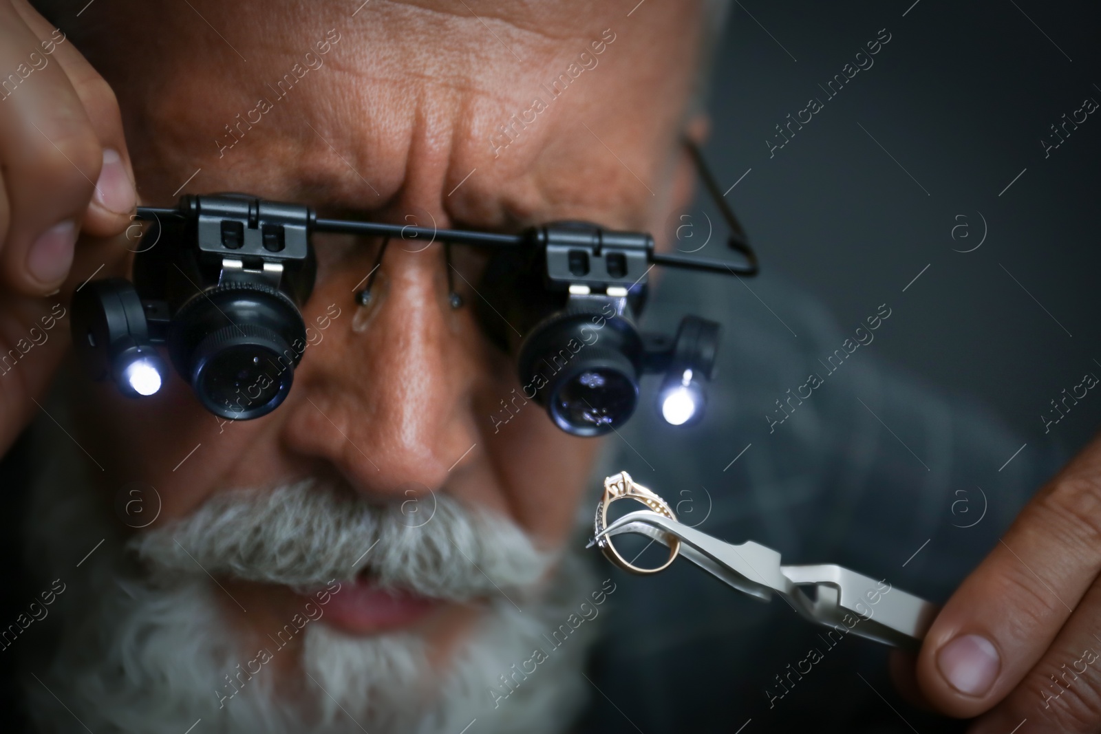 Photo of Male jeweler evaluating diamond ring in workshop, closeup view