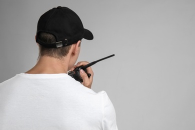 Male security guard using portable radio transmitter on color background