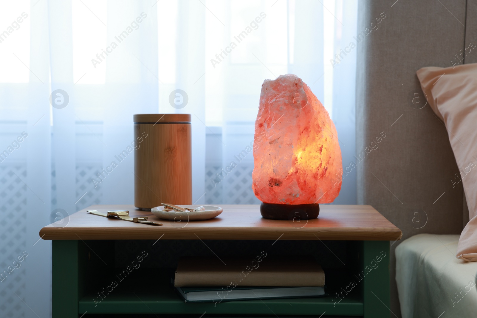 Photo of Himalayan salt lamp, air ionizer and accessories on nightstand in bedroom