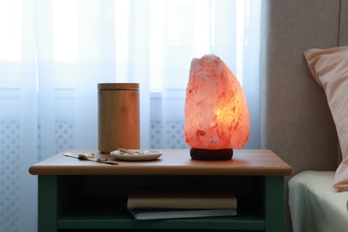 Photo of Himalayan salt lamp, air ionizer and accessories on nightstand in bedroom
