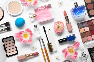 Photo of Flat lay composition with different makeup products and beautiful spring flowers on white background