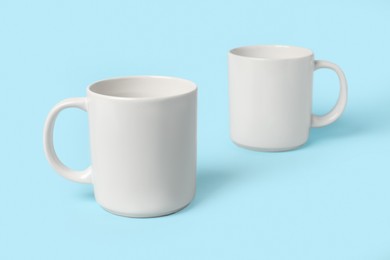 Photo of Two white ceramic mugs on light blue background