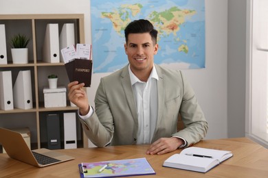 Travel agent with tickets and passports at table in office