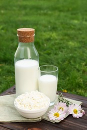 Photo of Tasty fresh milk and cottage cheese on wooden table outdoors