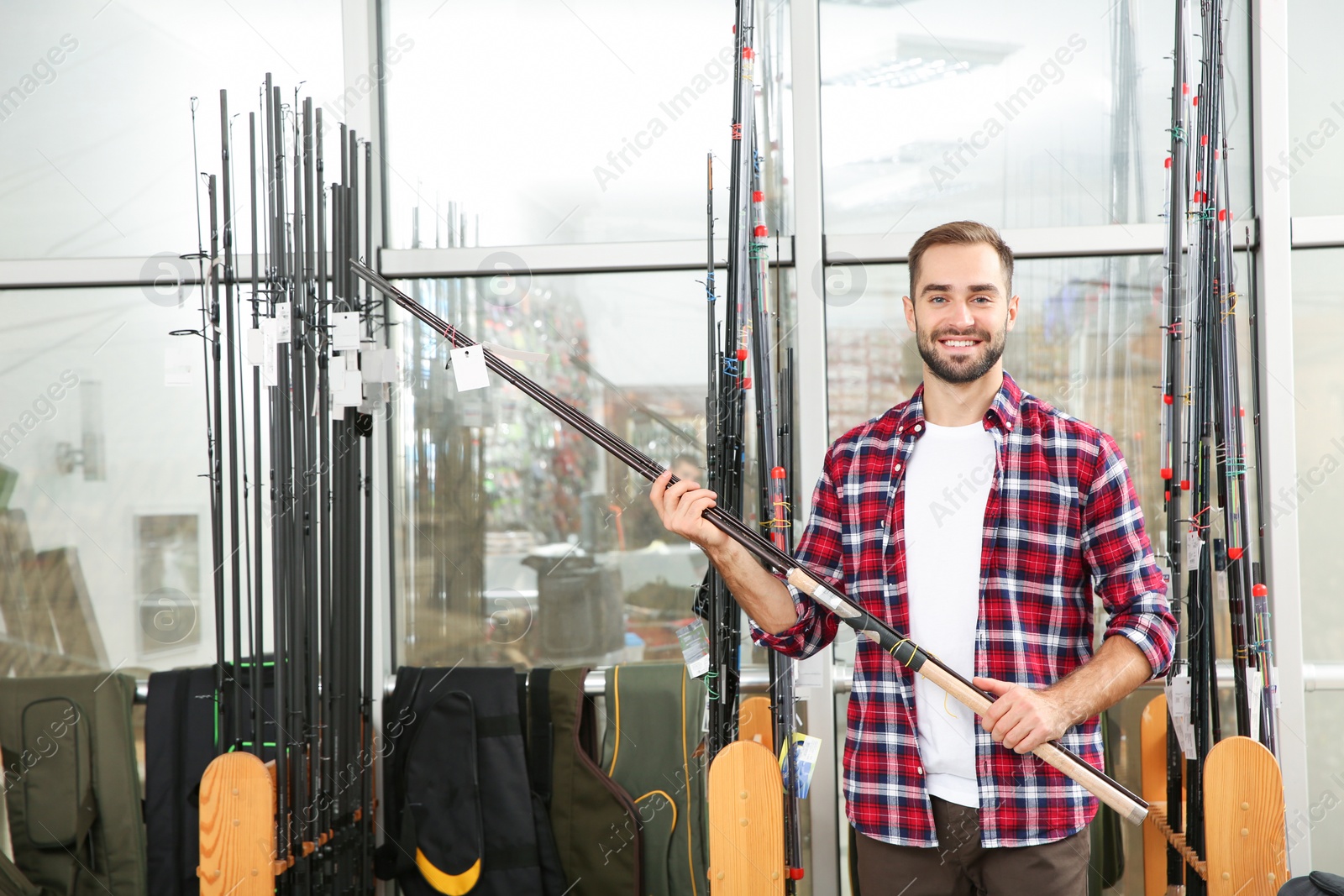 Photo of Man choosing fishing rod in sports shop. Space for text