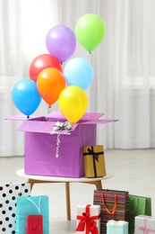 Photo of Gift box with bright air balloons and gift bags indoors