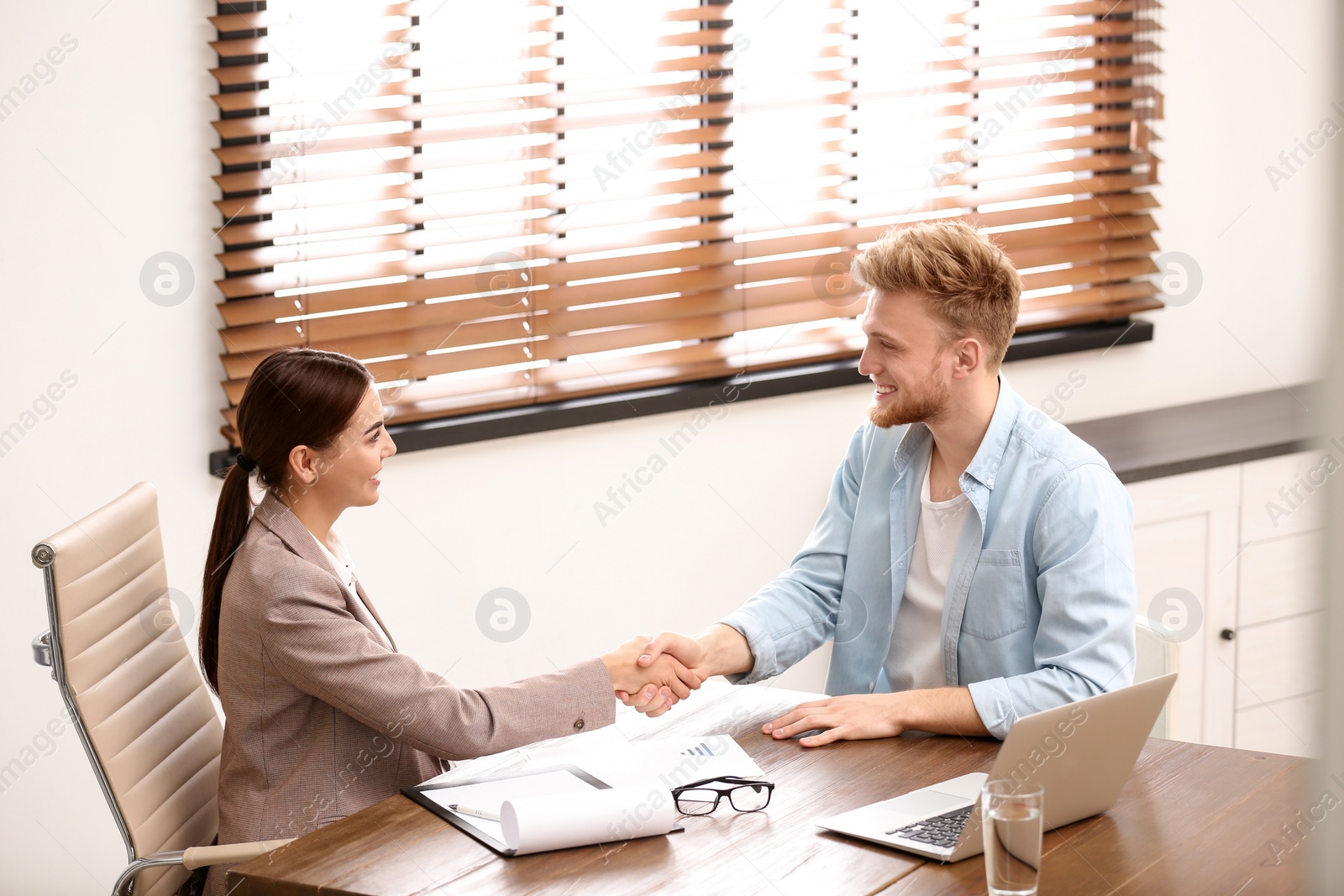 Photo of Female insurance agent shaking hands with client in office