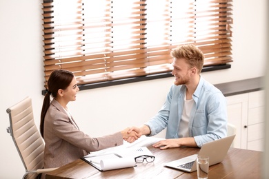 Female insurance agent shaking hands with client in office