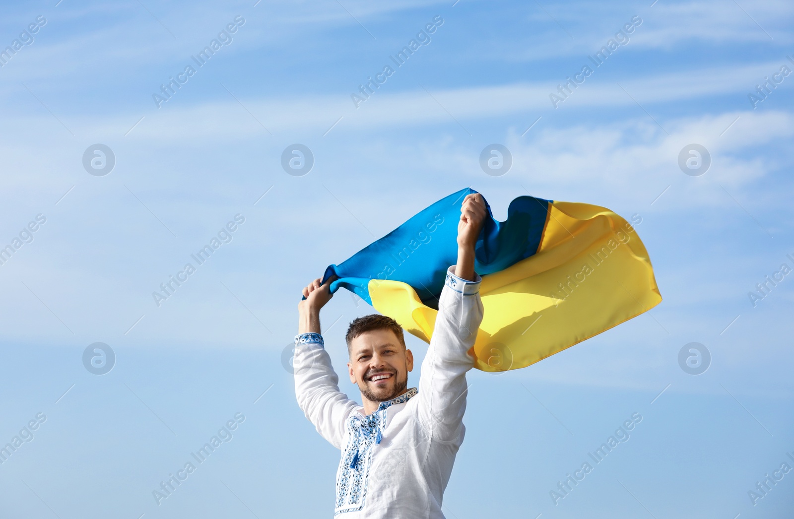 Photo of Man in vyshyvanka with flag of Ukraine outdoors