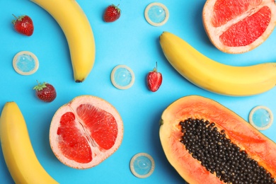 Photo of Flat lay composition with condoms and exotic fruits on blue background. Erotic concept