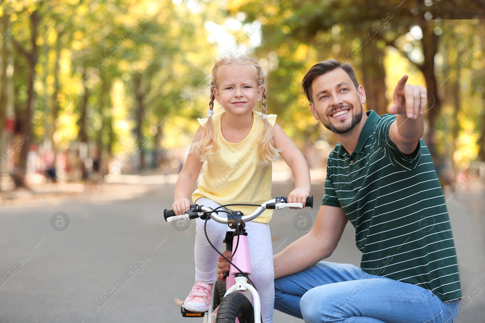 Photo of Father teaching daughter to ride bicycle on street