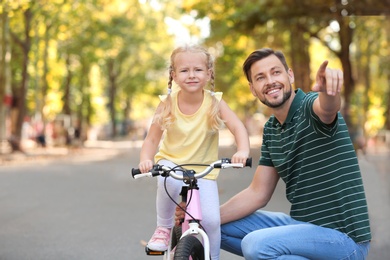 Father teaching daughter to ride bicycle on street