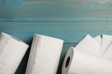 Photo of Rolls of white paper towels on light blue wooden table, flat lay. Space for text